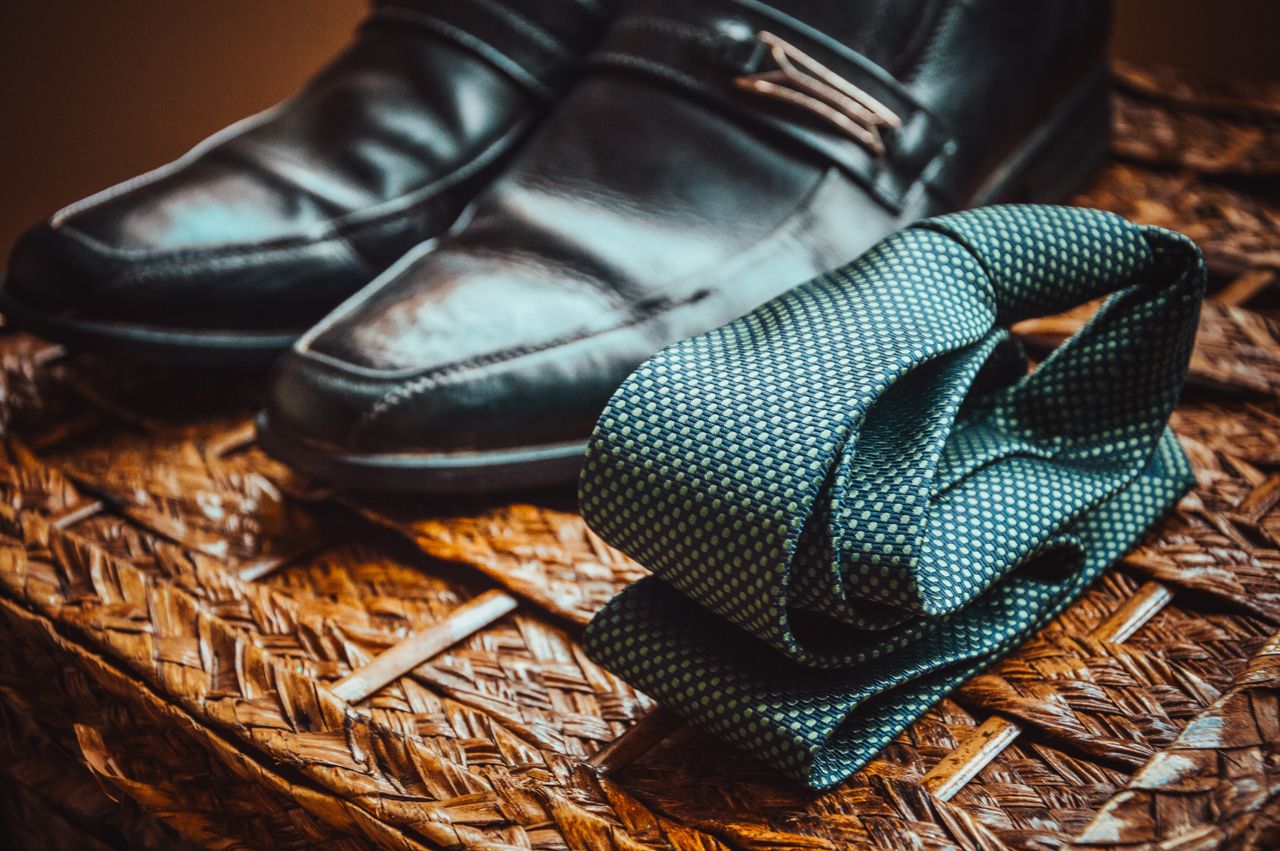 The Art of Drawing Readers In: Your attractive post title goes here Close-up of a stylish necktie and polished leather shoes resting on a woven wicker surface.